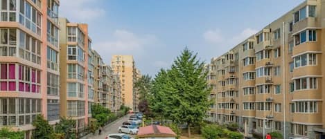 A residential area with multi-story apartment buildings, a parking lot, and a small fenced garden area.
