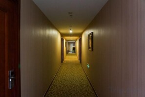 A hotel hallway with carpeted flooring, wooden doors, and framed pictures on the walls. - Yucheng Hotel (Beijing Tongzhou Dongzhimen Hospital) (Beijing)