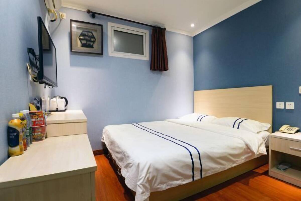 Een hotelkamer met een bed, nachtkastje en een klein bureau met stoel.