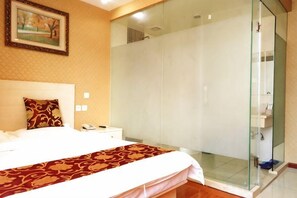 Une chambre d’hôtel avec un lit, une table de chevet, une douche en verre et un tableau au mur.