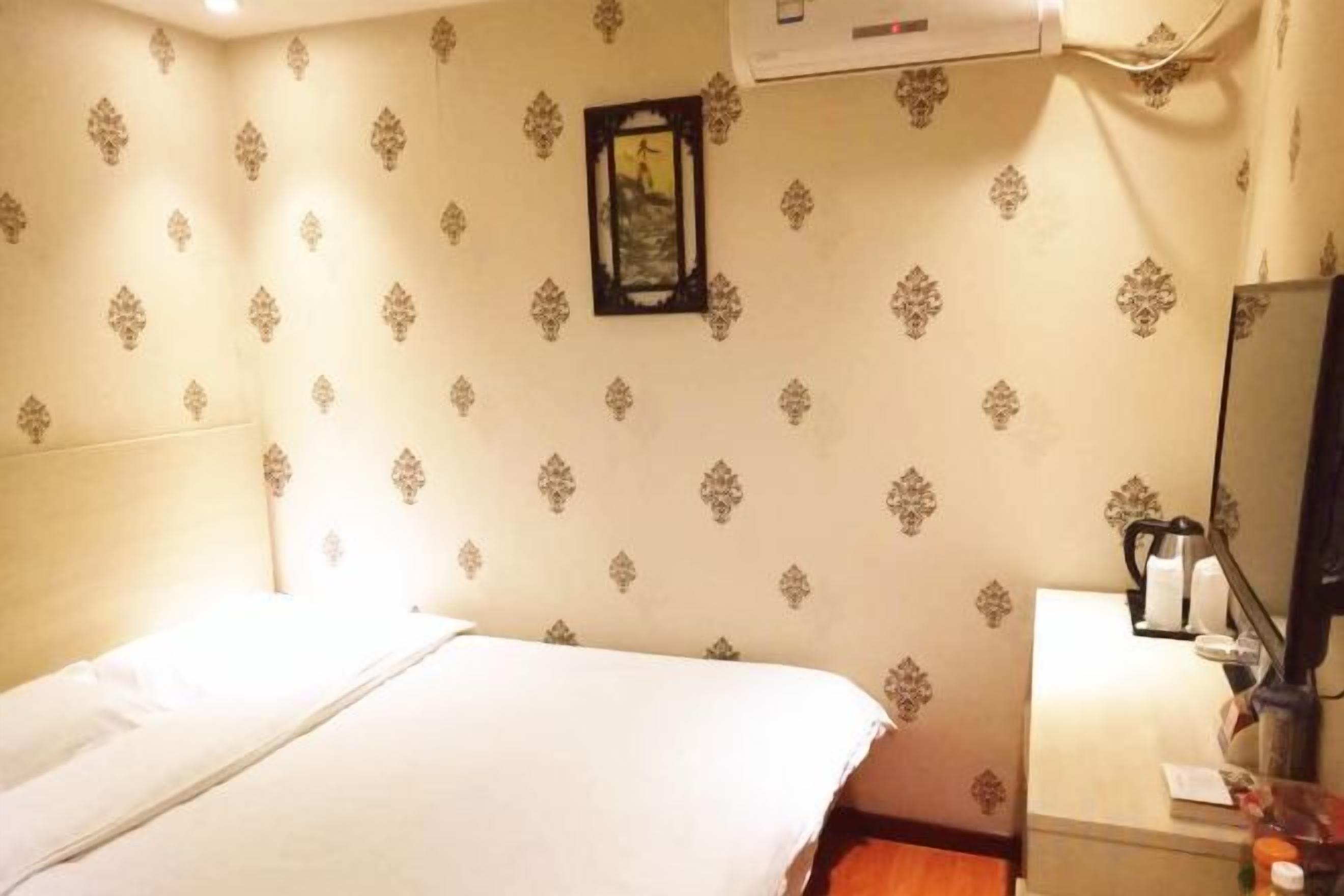 Una habitación de hotel con una cama, una mesita de noche, un espejo y un aire acondicionado instalado en la pared.