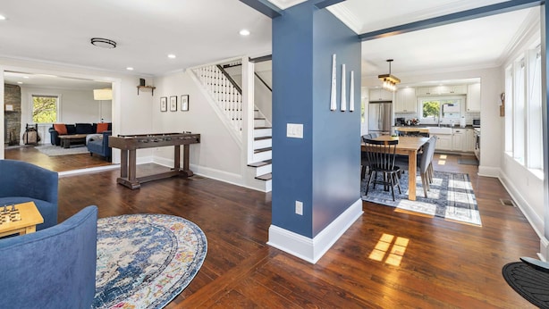 A spacious living room with a blue accent wall, hardwood flooring, and a central seating area with a coffee table and blue sofa.