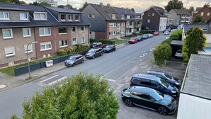 A residential street with parked cars and houses. - Am Quellberg Apartments Recklinghausen (Recklinghausen)