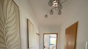 A hallway with a wooden floor, a door on the right, and a ceiling light fixture. - Am Quellberg Apartments Recklinghausen (Recklinghausen)