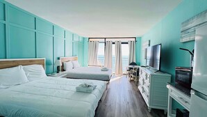 Et hotelværelse med to senge, et fjernsyn, en kommode og en balkon med gardiner.