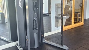 A gym with two cable machines, a mirrored wall, and a wooden door in the background. - SC5 Oceanfront beautiful condo right on the beach (Myrtle Beach)