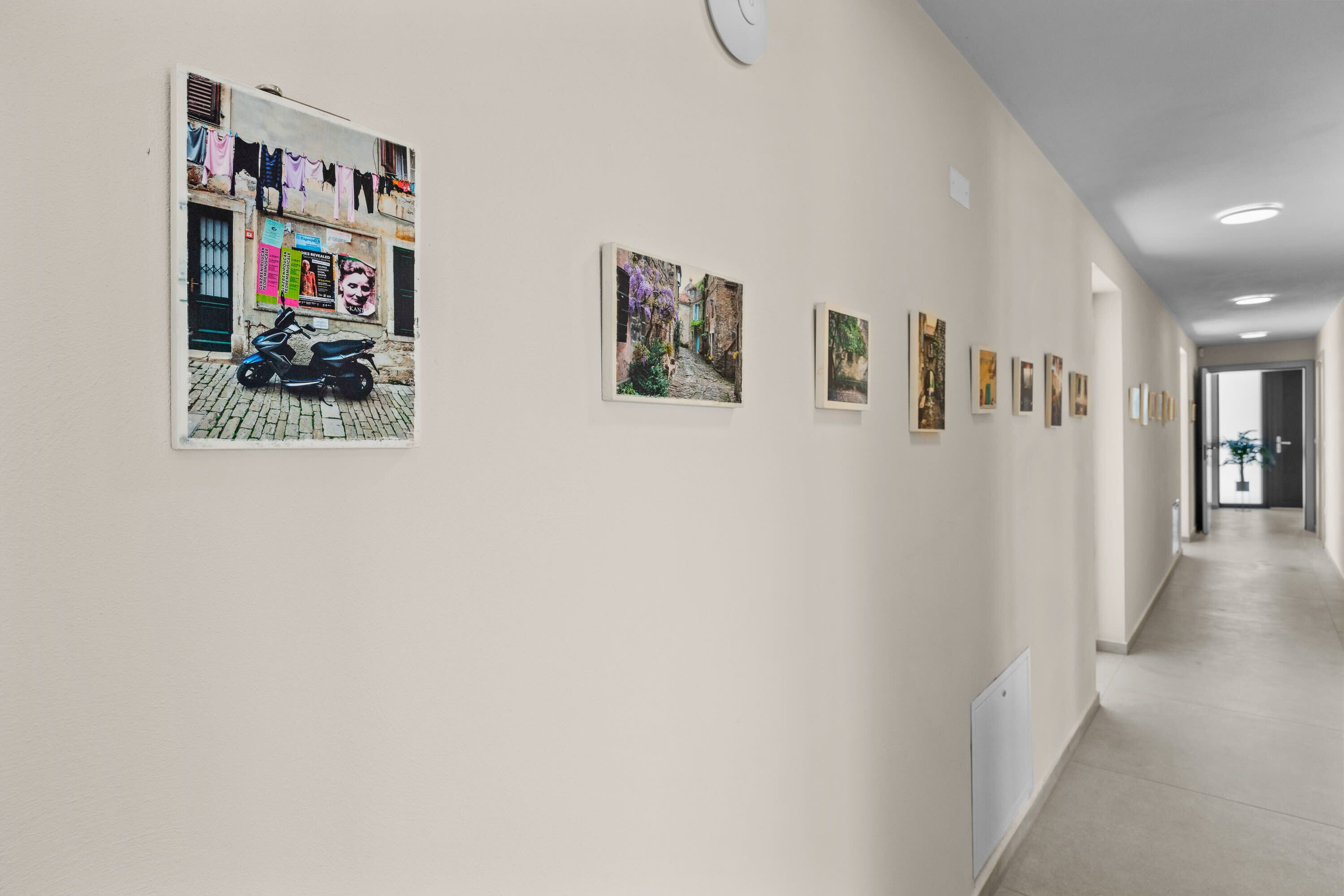 A hallway with art on the walls, a clock, and a door at the end.