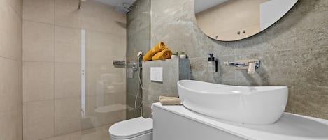 A modern bathroom with a large mirror, a white sink, and a shower area.