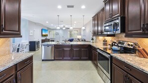 Una cocina moderna con alacenas de madera oscura, encimeras de granito, electrodomésticos de acero inoxidable e iluminación colgante.