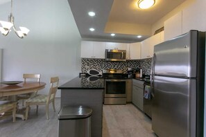 A compact kitchen with a dining area, stainless steel appliances, and a patterned backsplash. - Beachfront 3-Bedroom Villa in Palmas del Mar(BV179) (Humacao)