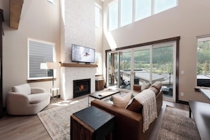 Relax in this spacious living room with a fireplace, flat-screen TV, and comfortable seating area leading to an outdoor deck.
