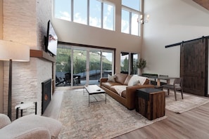 Relax in this stylish living room with a fireplace, TV, and dining area, featuring a sliding glass door to an outdoor space.