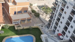 Un immeuble résidentiel doté d’une piscine, d’un petit jardin et d’une aire de jeux.