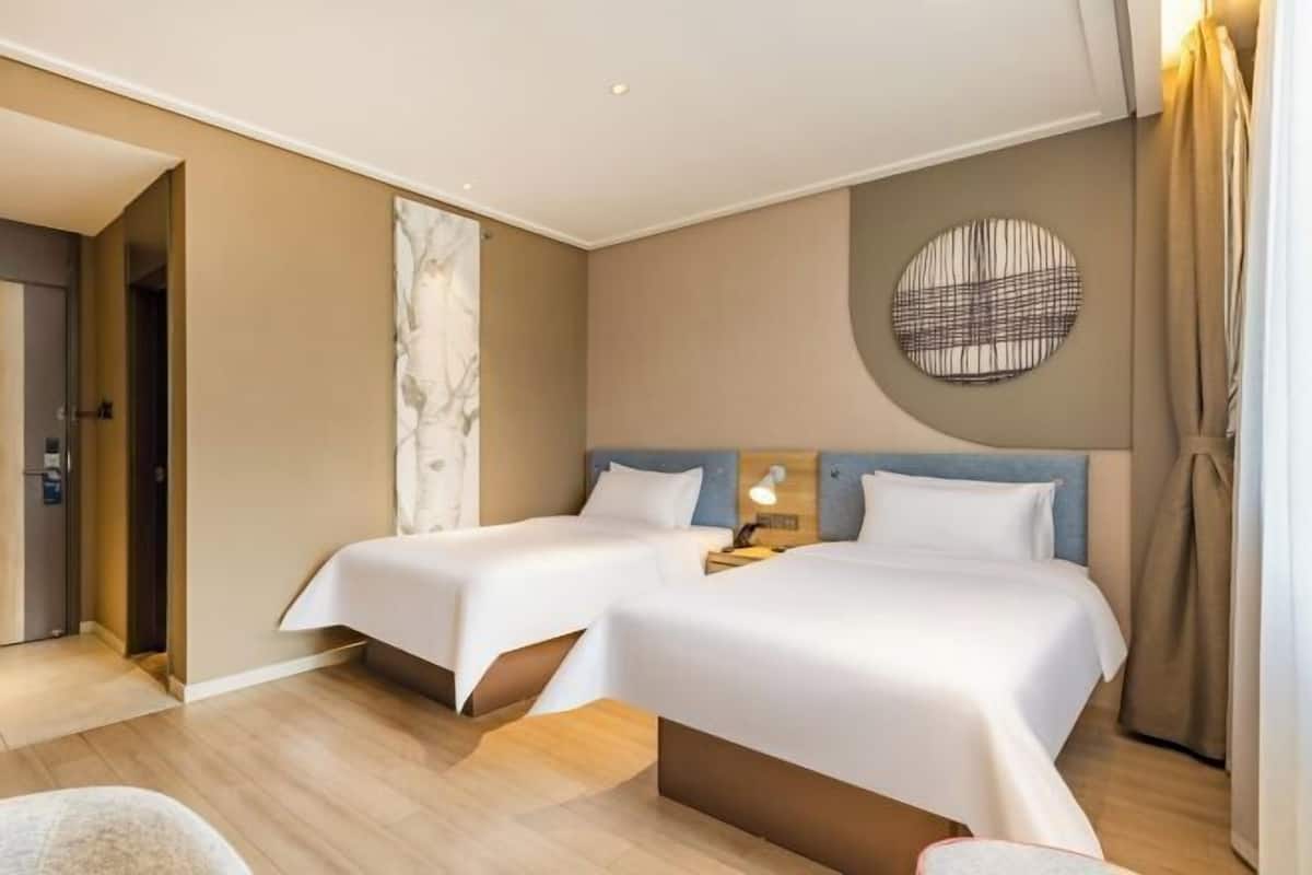 A hotel room with two beds, a marble wall, a round wall decoration, and a wooden floor.