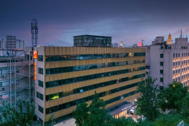 A multi-story building with a modern architectural design, featuring a flat roof and a series of windows.