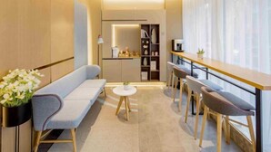 Une pièce moderne et bien éclairée, avec un canapé, une petite table ronde et des tabourets de bar.