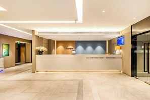 A hotel reception area with a reception desk, a flat-screen TV, and a vase of flowers. - Homeinn · neo (Tianjin Railway Station Binjiang Avenue Pedestrian Street) (Tianjin)
