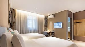 Une chambre d’hôtel avec deux lits, un bureau, une chaise, une télévision et une fenêtre avec des rideaux.