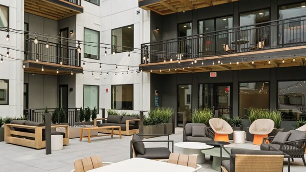 Un espace extérieur moderne, aménagé avec plusieurs niveaux de balcons, des guirlandes lumineuses et différents types de sièges.