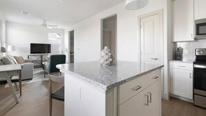A modern kitchen with white cabinets, a granite countertop, and stainless steel appliances.