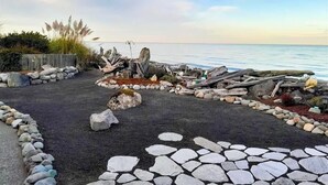 Uma trilha costeira com limite de pedra, que leva a uma estrutura de madeira à beira-mar.