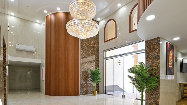A modern lobby with a large chandelier, marble walls, wooden accents, and a glass entrance. - Diyar AlSaliheen Serviced Apartments (Madinah)