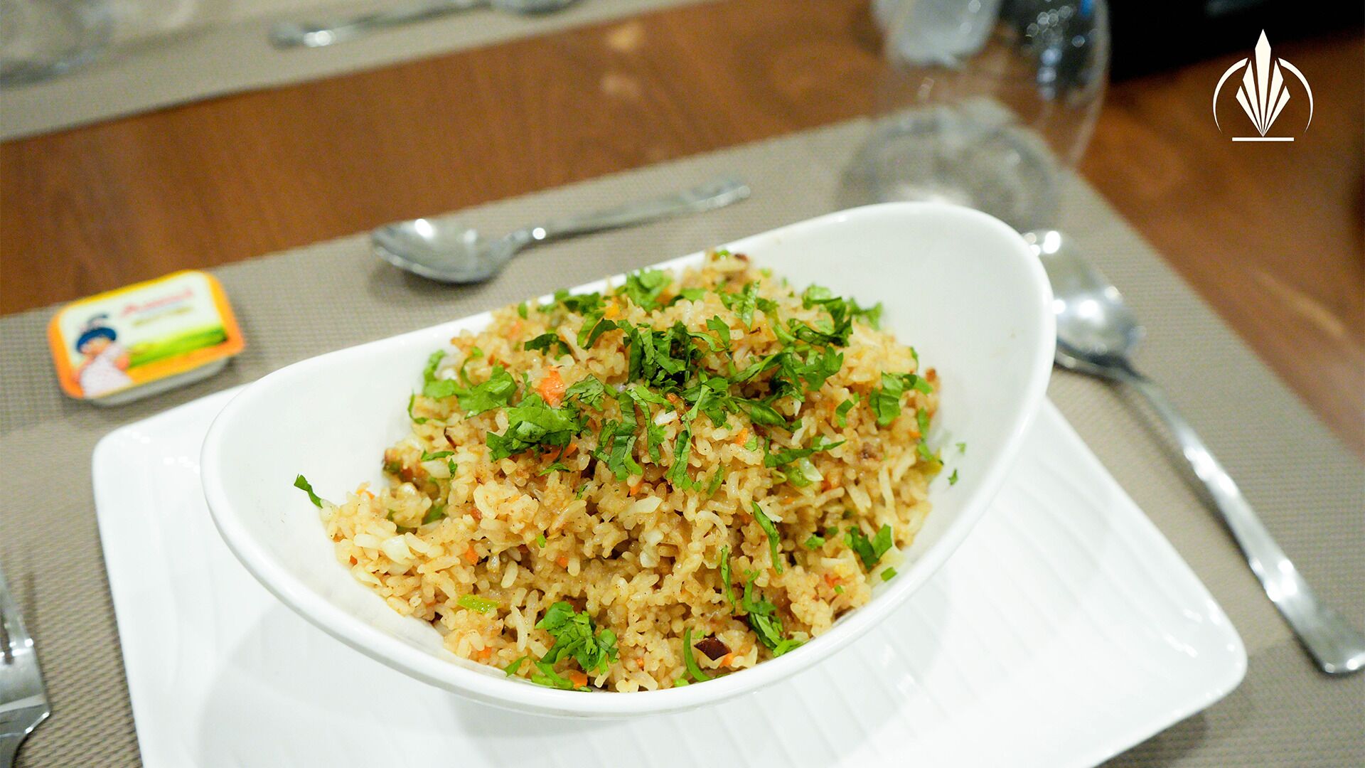 A bowl of fried rice garnished with herbs, placed on a white plate.