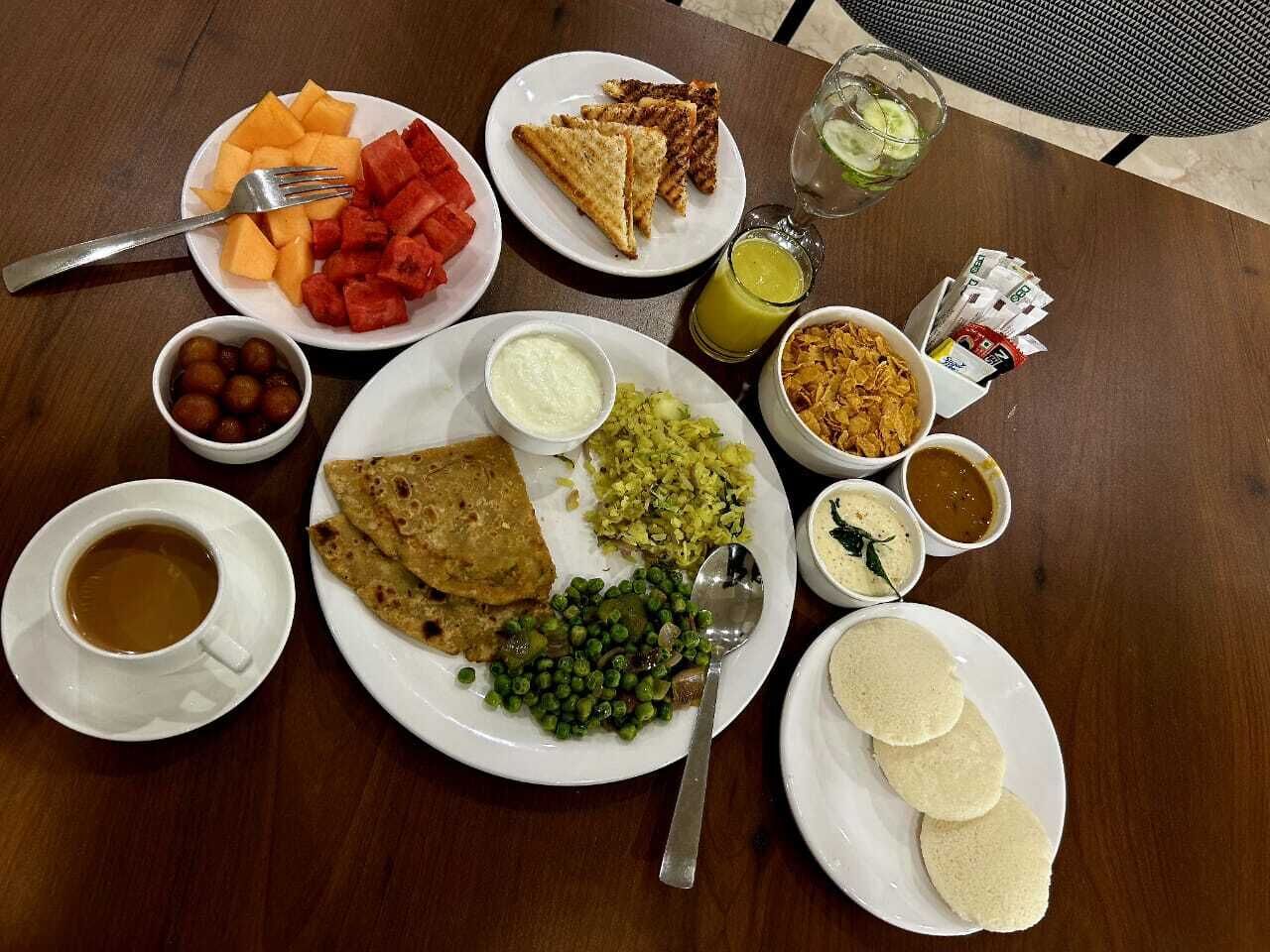 A table with various dishes including flatbreads, vegetables, and a cup of tea.