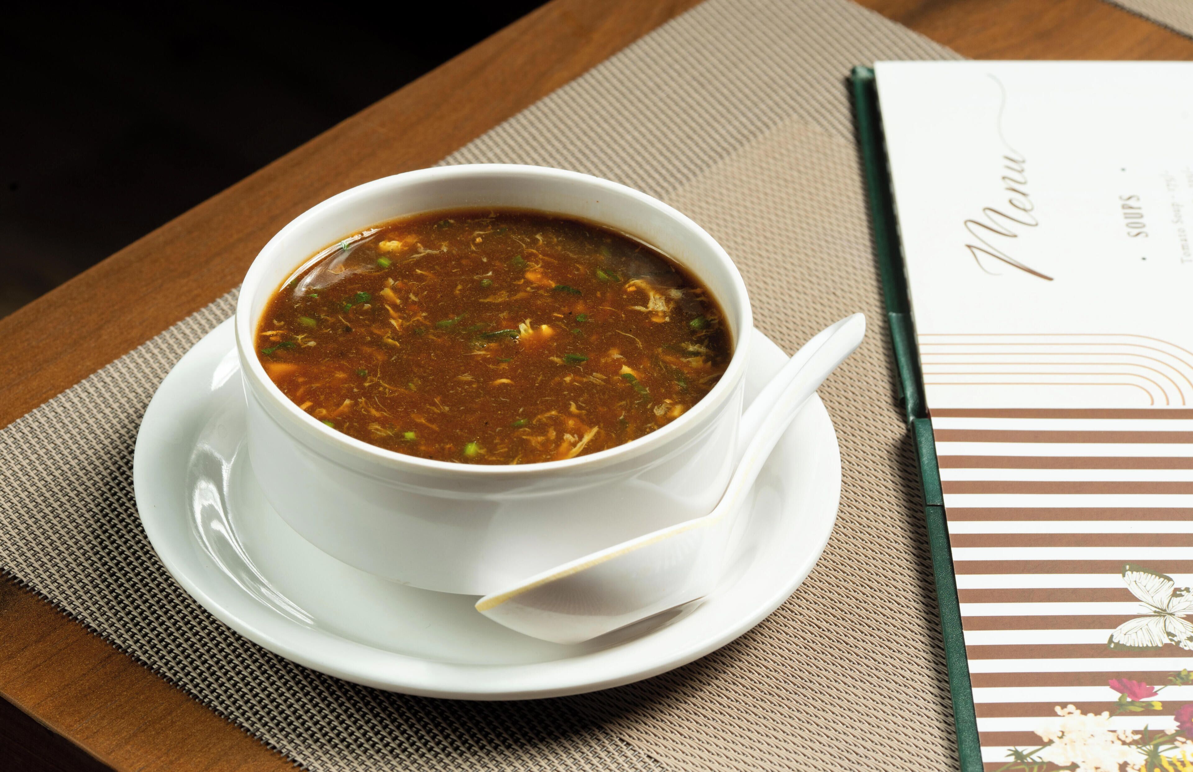 A bowl of soup on a table with a menu beside it.