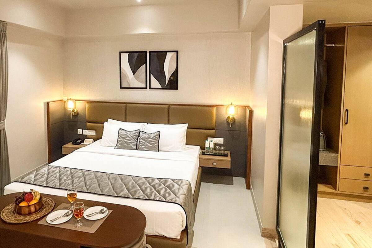 Ein modernes Hotelzimmer mit einem großen Bett, Nachttischen, einem Schreibtisch und einem Kleiderschrank.