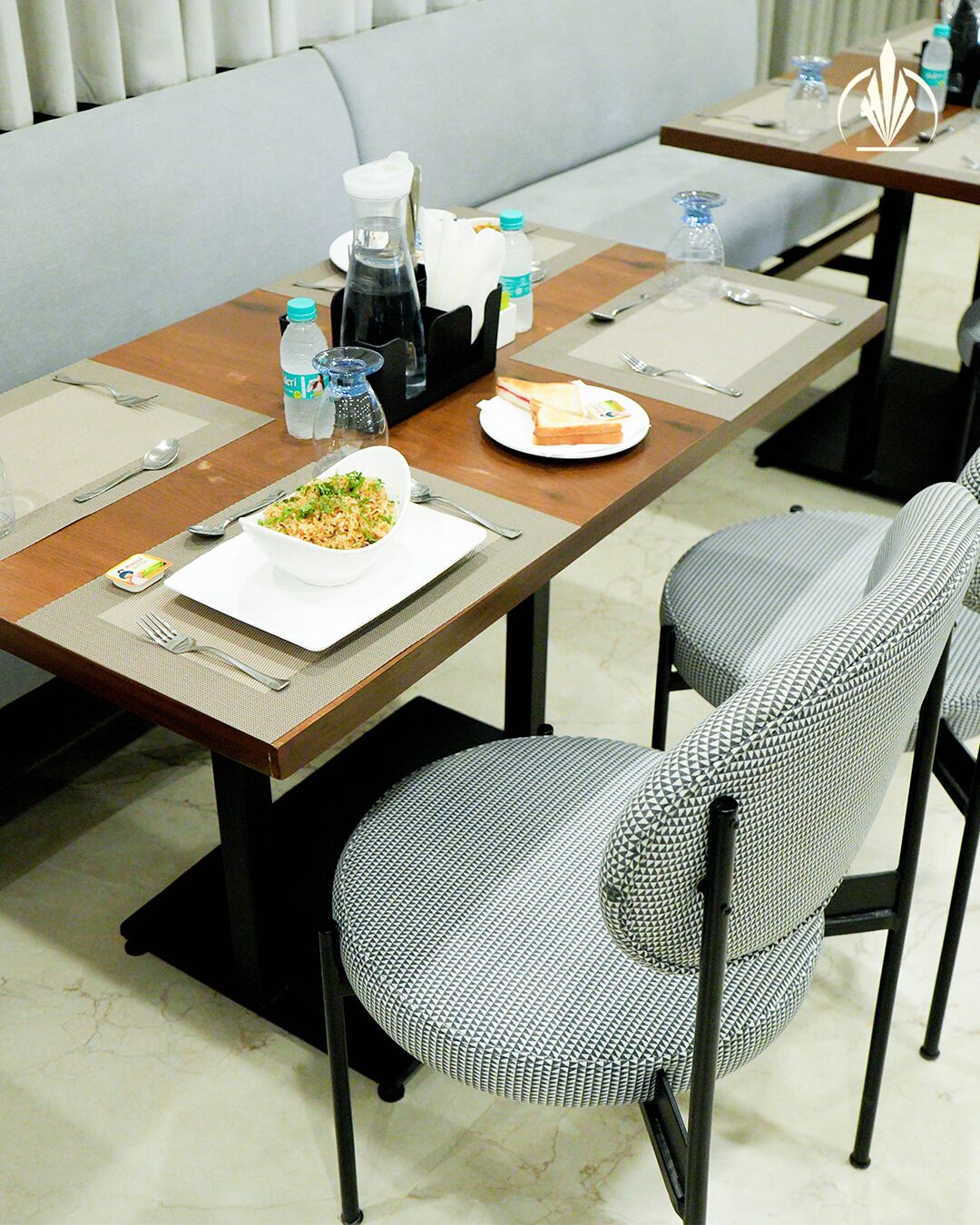 A dining area with a table set for two, including plates, cutlery, and a bottle of water.