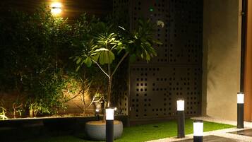 An outdoor area with a wooden wall, a potted plant, and a pathway with bollards.