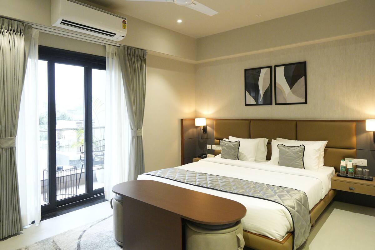 Ein Hotelzimmer mit Bett, Nachttischen, einem Schreibtisch und Blick ins Freie.