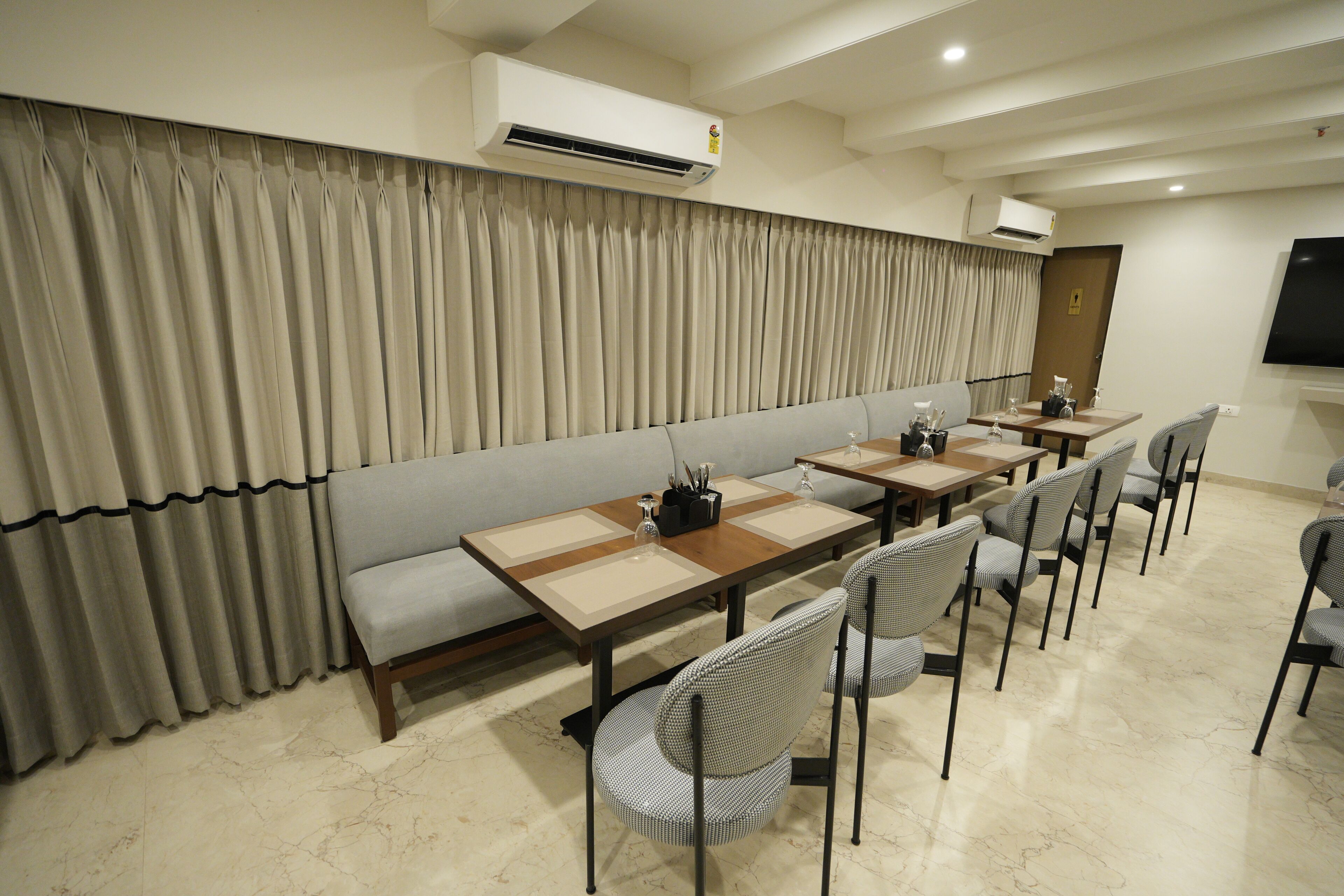 A conference room with a long table, chairs, and a sofa. There are air conditioning units on the ceiling.