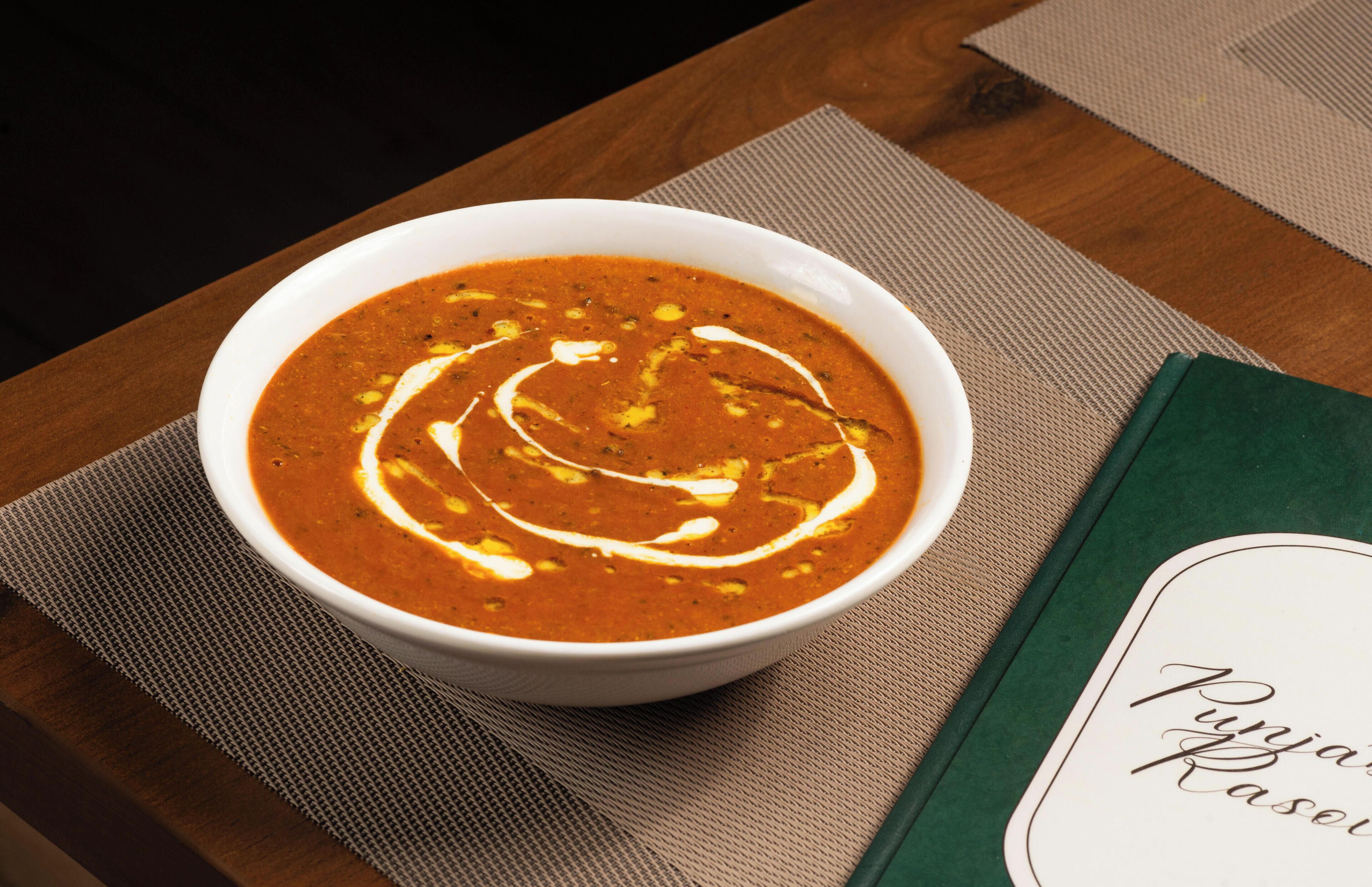 A bowl of soup on a table with a placemat and a book with a nameplate.