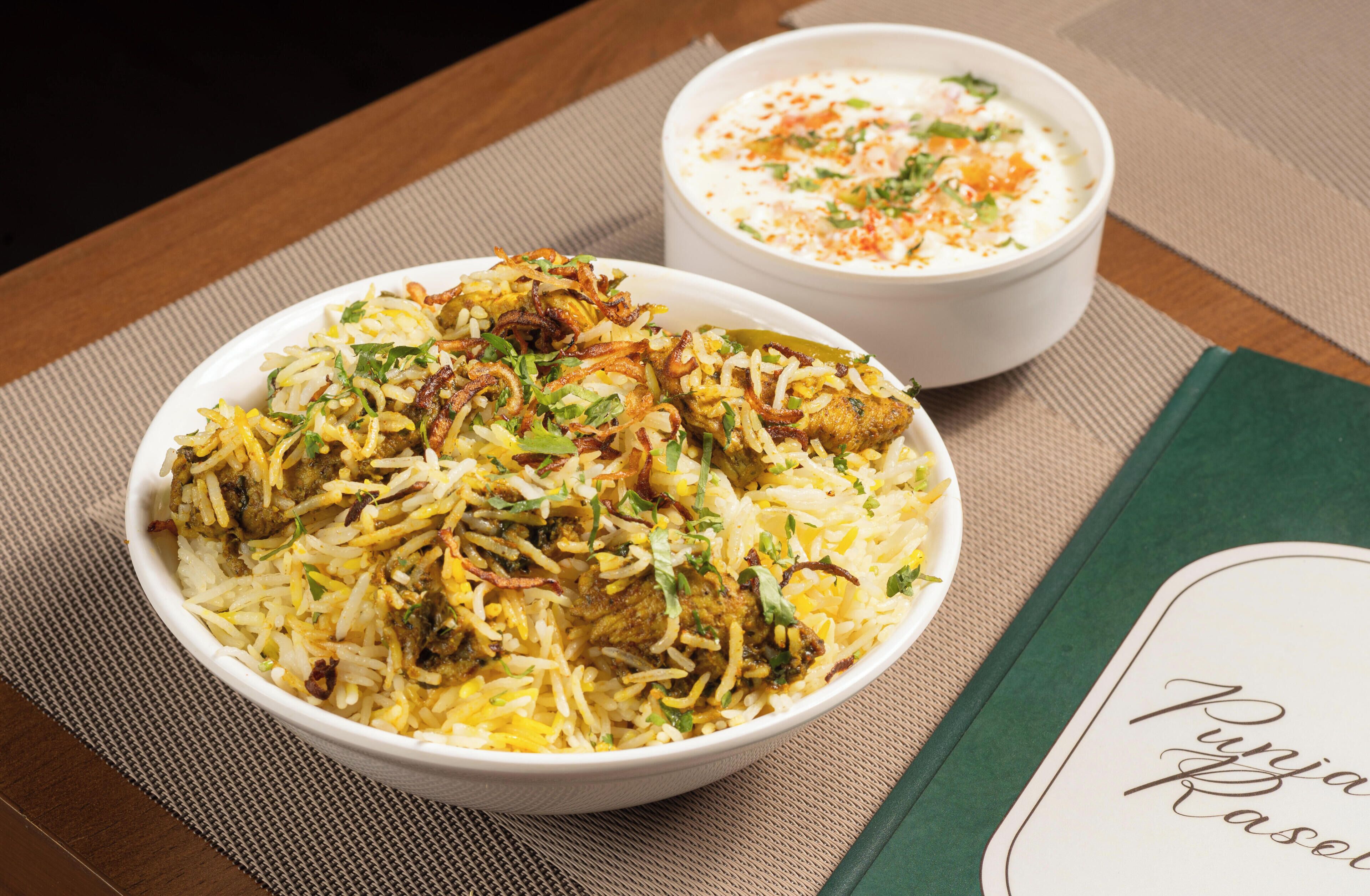 Un bol de biryani et un bol de raita sur une table, avec un set de table.