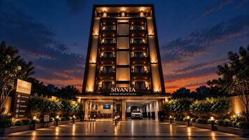 A multi-story hotel with a sign indicating luxury rooms, a banquet, a restaurant, meetings, and parking.