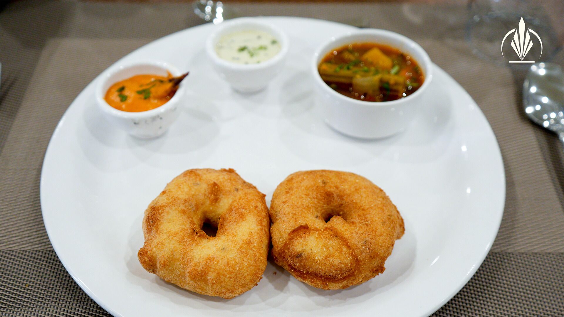 A plate with two fried dough items and three small bowls of dipping sauces.