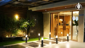 A hotel entrance with a reception desk, a sign reading "IVANTA", and a well-lit outdoor area with potted plants and bollards. - SIVANTA BY BOMBAY GROUP OF HOTELS NAGPUR (Nagpur)