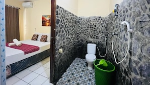 Una habitación pequeña con cama, inodoro y zona de ducha.