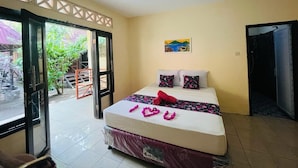Habitación de hotel con cama, un cuadro en la pared y vistas a través de la puerta abierta.