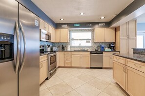 A modern kitchen with stainless steel appliances, wooden cabinets, and a tiled backsplash.