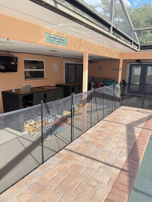Uma área externa com mesa e cadeiras de pátio, e um espaço cercado para brincar.