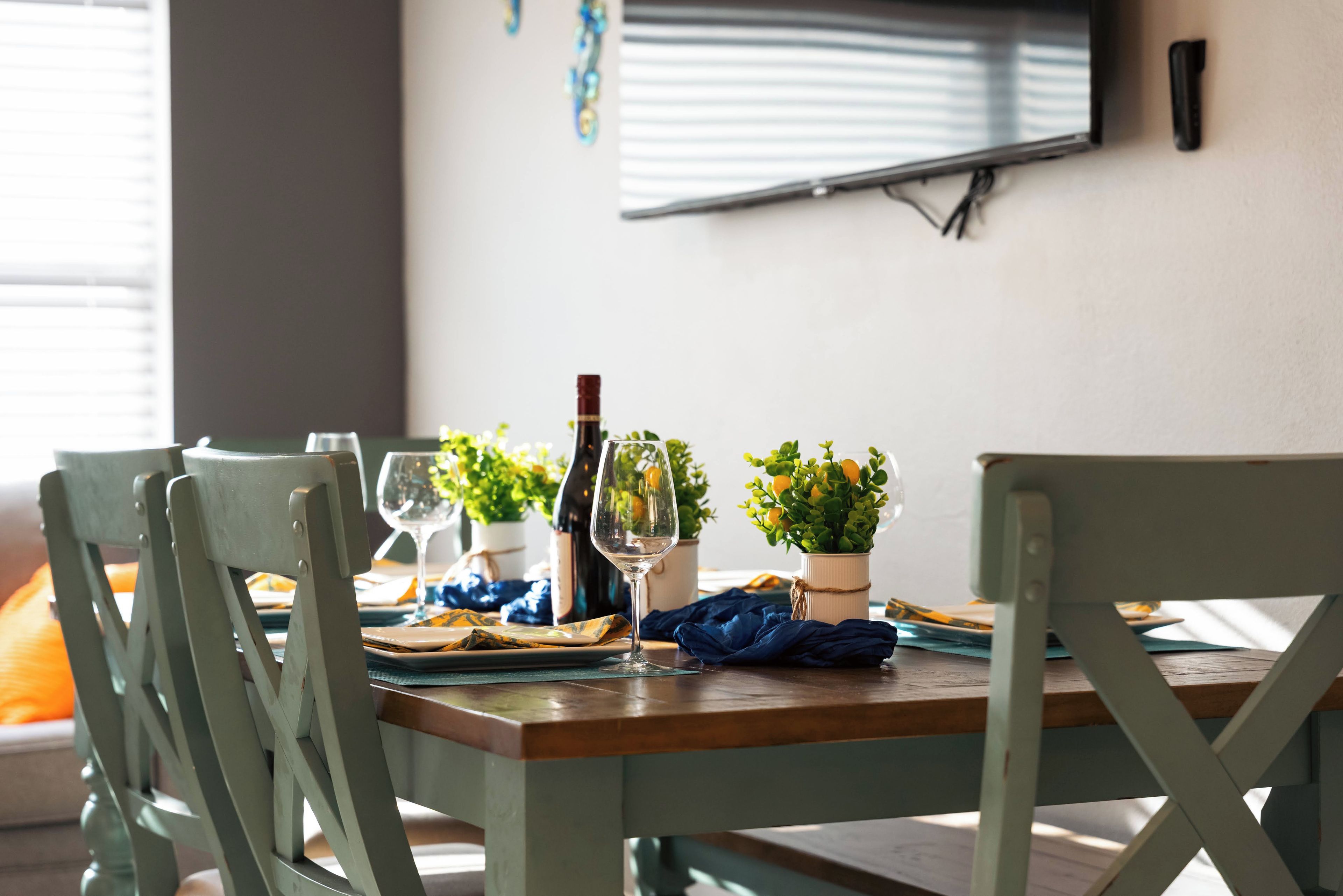 Een eettafel gedekt met borden, glazen, een fles en een klein plantje.