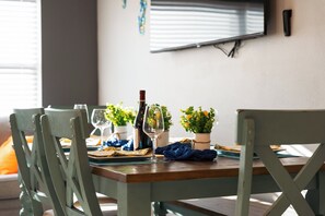 Une table à manger dressée avec des assiettes, des verres, une bouteille et une petite plante.