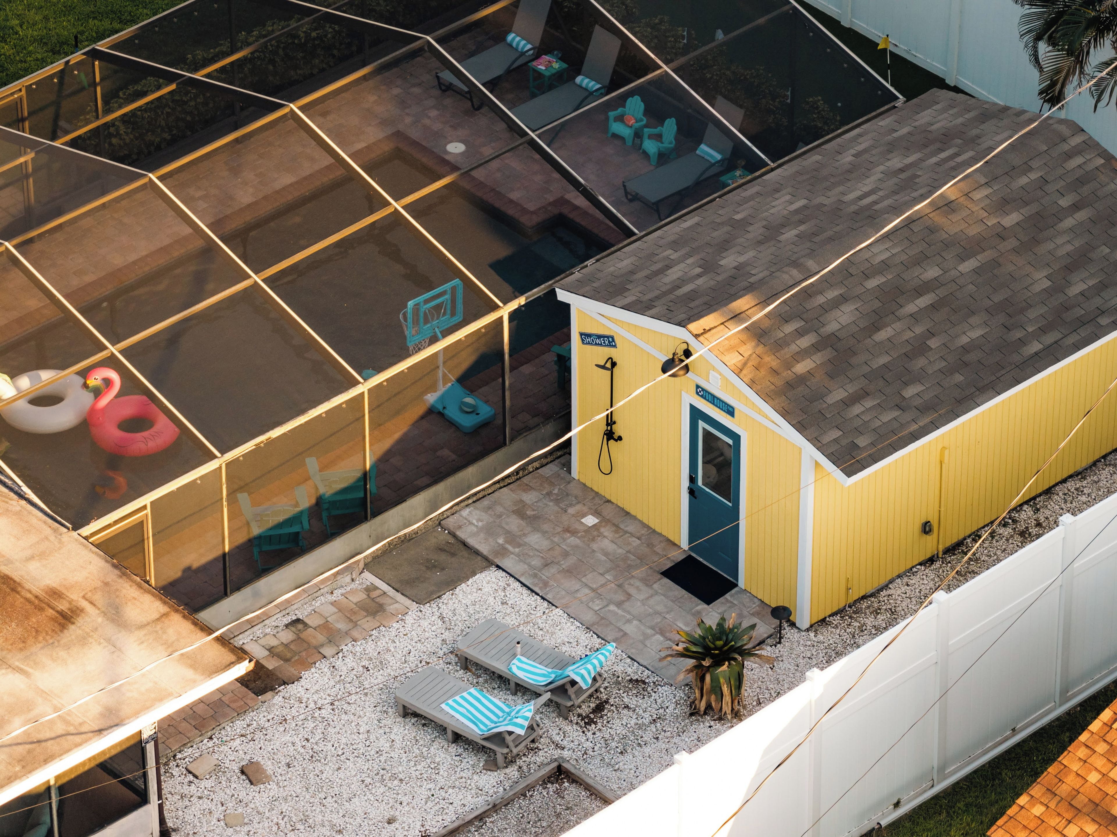 Il s’agit d’une propriété résidentielle dotée d’un patio fermé par des baies vitrées, d’un bâtiment jaune avec une porte et d’un espace extérieur aménagé pour s’asseoir.