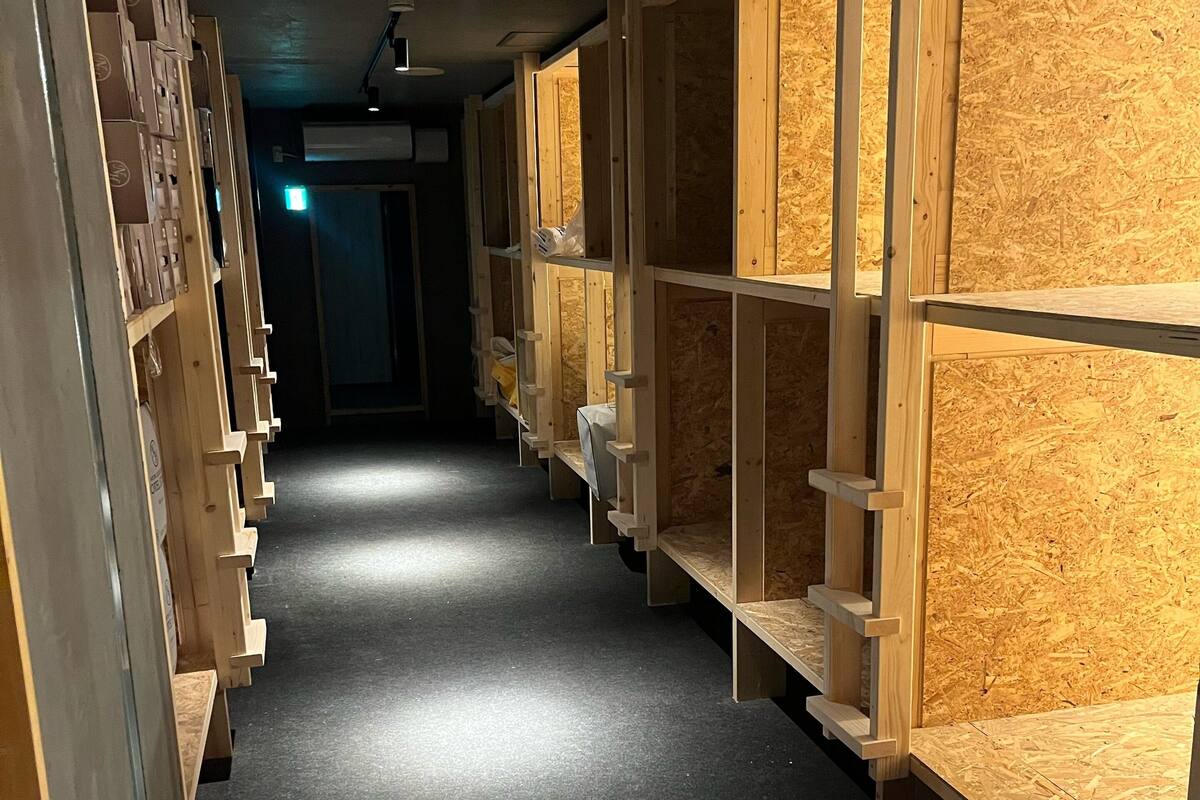 A corridor with wooden shelving units on both sides, leading to a door at the end.