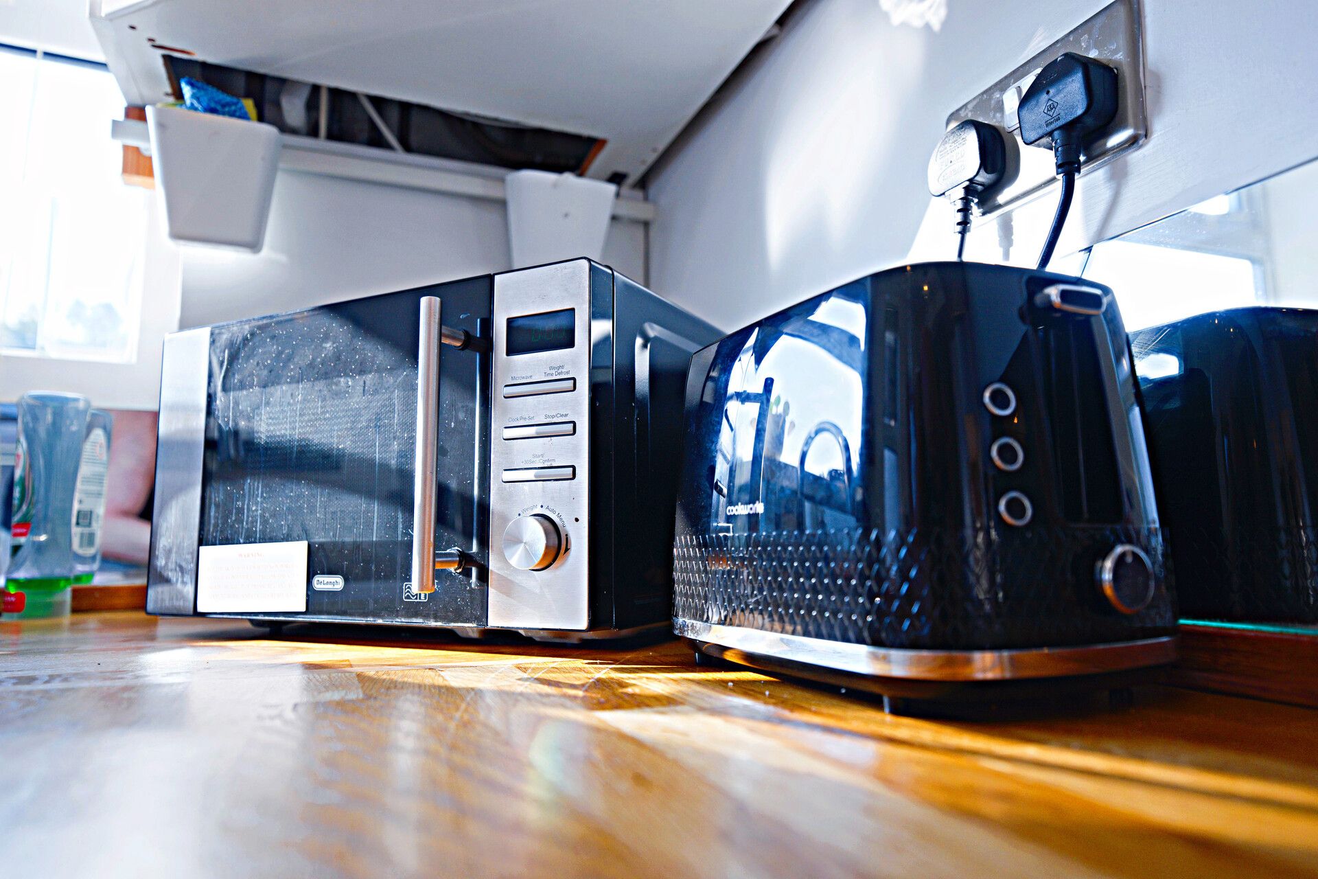 Deux appareils de cuisine, un grille-pain et un four à micro-ondes, sont posés sur un plan de travail en bois.