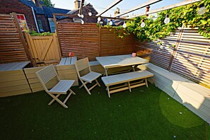 A wooden deck with a table and chairs, surrounded by a wooden fence and greenery. - Upscale Family Home, Beautiful Setting (Merseyside)