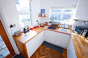 Une cuisine compacte dotée de plans de travail en bois, d’un four encastré et d’une fenêtre laissant entrer la lumière naturelle.